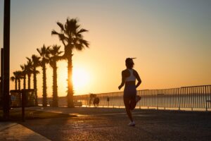 Jeune femme en train de courir au lever du soleil au bord de la mer. Une jeune femme s'amuse à courir dehors par une belle matinée d'été au bord de la mer.